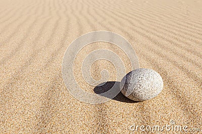 White round stone lying on clean sand. Concept of balance, harmony and meditation. Minimalism Stock Photo