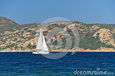 White sailboat along the granite coast of Sardinia Editorial Stock Photo