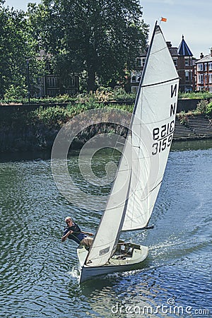 A white sails sailboat maneuvers on the River Thames near Richmond, London Editorial Stock Photo