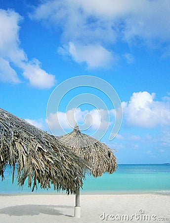 White sandy beach with sunshades made of palm trees Stock Photo