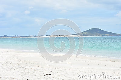 White sandy beach with volcano cone in distance Stock Photo