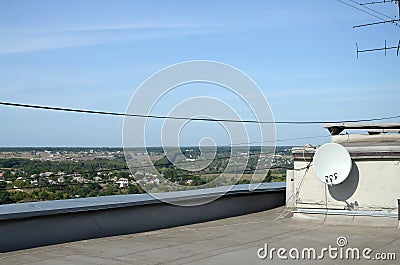 White satellite dish with three converters mounted on residental building rooftop concrete wall. Satellite television Stock Photo