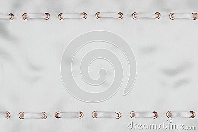 White satin ribbon inserted in the gold rings on white silk, trendy background. Stock Photo