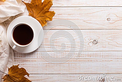 White scarf, cup of coffee and dry yellow leaves on a wooden table. Autumn mood, copy space Stock Photo