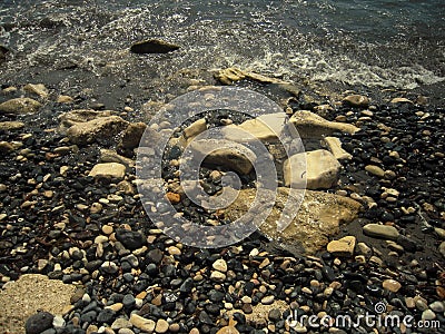 White sea rocks and pebbles washed by wave. Stock Photo