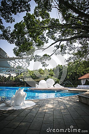 white Shell conch foam sculpture sea blue water sunshine swimming pool trees Stock Photo
