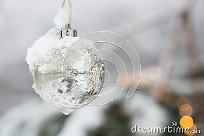 White Silver Beautyful Christmas Ornament Bauble haning at a Fir Tree with Snow Stock Photo