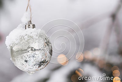 White Silver Beautyful Christmas Ornament Bauble haning at a Fir Tree with Snow Stock Photo