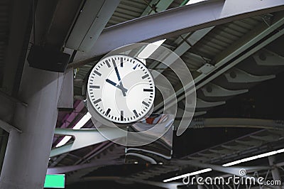 White simple clock hanging on pole in station Stock Photo