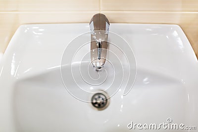 White sink or wash basin with shiny chromed faucet against the background of wall. Fragment of modern bathroom interio Stock Photo