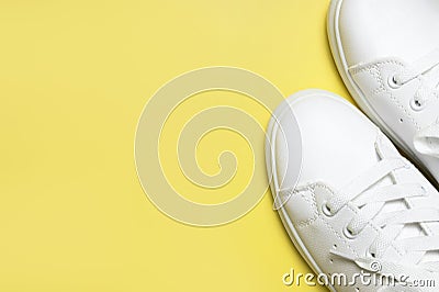 White sneakers on yellow background top view flat lay. Stylish youth women`s leather sneakers, sports shoes, genuine leather Stock Photo