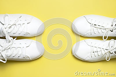 White sneakers on yellow background top view flat lay. Stylish youth women`s leather sneakers, sports shoes, genuine leather Stock Photo