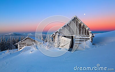 The white snow glows the color of the sky. The old huts stand in the valleys. Cold winter day. Stock Photo