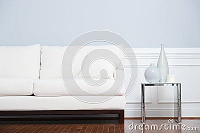 White Sofa and Glass End Table Against Blue Wall Stock Photo