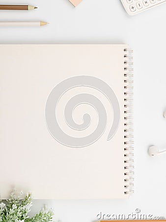 White spiral notebook surrounded by pencils, headphones and flowers, with copy space Stock Photo