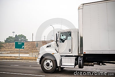 Powerful day cab big rig semi truck with box trailer delivering cargo running on the highway road with fire smog Stock Photo
