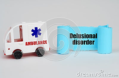 On a white surface, an ambulance and a blue paper sign with the inscription - Delusional disorder Stock Photo