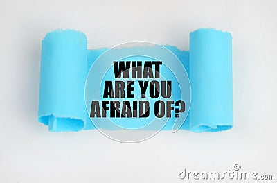 On a white surface, a blue scroll of paper with the inscription - WHAT ARE YOU AFRAID OF Stock Photo