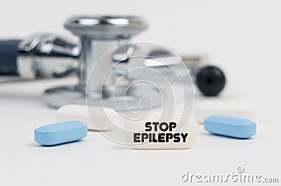 On a white surface lie pills, a stethoscope and a tablet with the inscription - STOP EPILEPSY Stock Photo