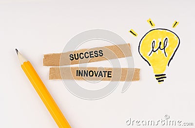On a white surface, a luminous light bulb and pieces of paper with the inscription - Success Innovate Stock Photo