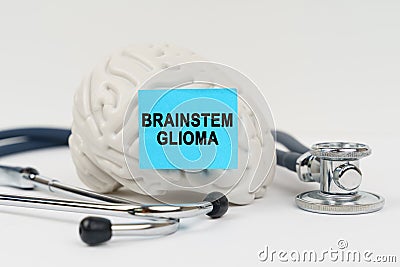 On a white surface next to the stethoscope lies a brain on which a sticker with the inscription - Brainstem glioma Stock Photo