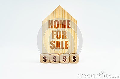 On a white surface stands a wooden model of a house with the inscription - Home For Sale Stock Photo