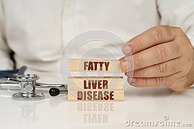 On a white surface, a stethoscope and wooden plates with the inscription - Fatty liver disease Stock Photo