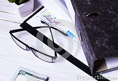 On a white table is a folder for papers, money and glasses in a black frame. Business concept close up Stock Photo