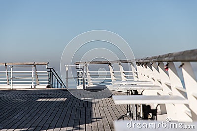 White tables on a sunlit wooden pier. Stock Photo