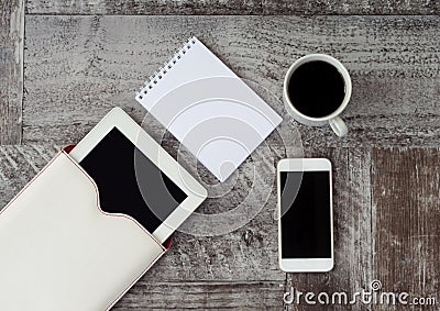 White tablet, phone, cup of coffee and notebook are on the table. Work at home. Freelance Stock Photo