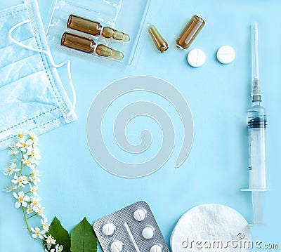 White tablets, glass ampoules, a syringe and cherry blossoms are arranged on alight blue background. Spring allergy Stock Photo