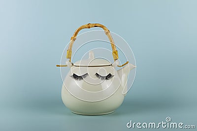 White teapot with eyes on a green background Stock Photo