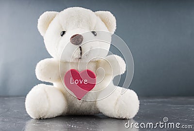 White teddy bear with love letter on red heart gray background. Say i you for valentine `s day concept. Stock Photo