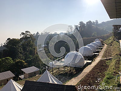 White tent for guests are hosted on wooden podium on camping Stock Photo