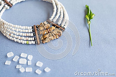 White and tiger stone beads necklace on a blue background with refined sugar and plant Stock Photo