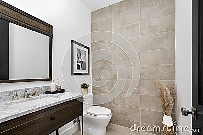 White toilet and a white sink against a tiled wall in a bathroom, Editorial Stock Photo