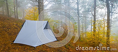 White touristic tent stay on mount slope in dense mist Stock Photo