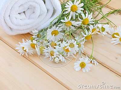 White towel and camomile bouquet on the natural wood planks Stock Photo