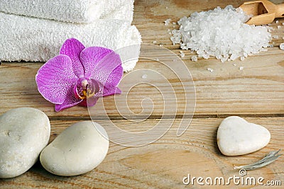 White towels, bath salts and stones for a hot massage on a wooden table. Stock Photo