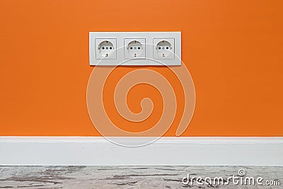 White triple outlet on orange wall Stock Photo