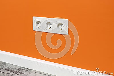 White triple outlet on orange wall Stock Photo