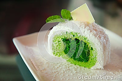 White tropical coconut cake with green pandan flavor on shredded coconut filling, topped mint leaves and white chocolate Stock Photo