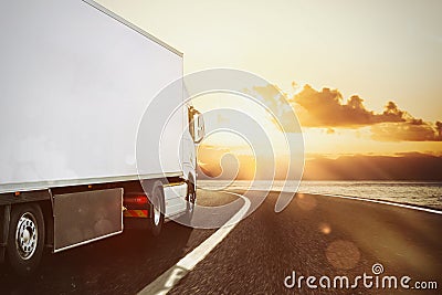 White truck moving on the road in a natural landscape at sunset Stock Photo