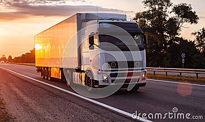 White truck with refrigerated semitrailer transport frozen food on the highway in the evening against the backdrop of Stock Photo