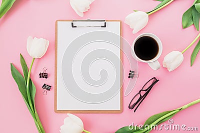 White tulips flowers with mug of coffee, clipboard and glasses on pink background. Blogger concept. Flat lay, top view. Stock Photo