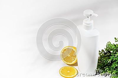 White unbranded bottle with lemon and green plants. Container with dispenser natural cosmetic products. Blank flacon for lotion, Stock Photo