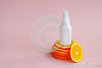 White unbranded plastic spray bottle and orange slices podium on pink background. Natural organic spa cosmetics and liquid Stock Photo