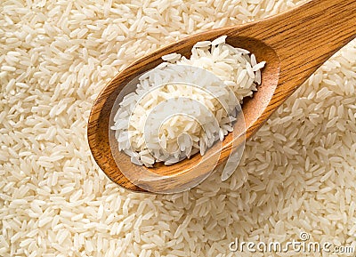 White uncooked, raw long grain rice full frame with wooden spoon top view flat lay from above Stock Photo