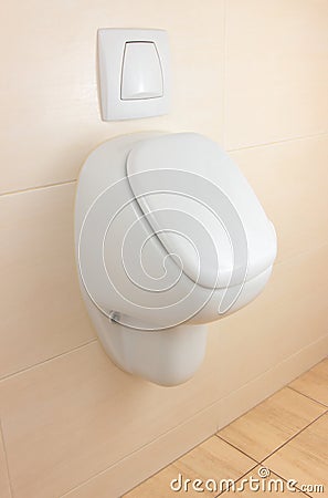 White urinal on beige tiled wall Stock Photo