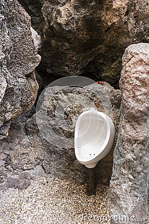 White urinal for male decoration on wall mountain in natural hill. strange idea install urine flush Stock Photo